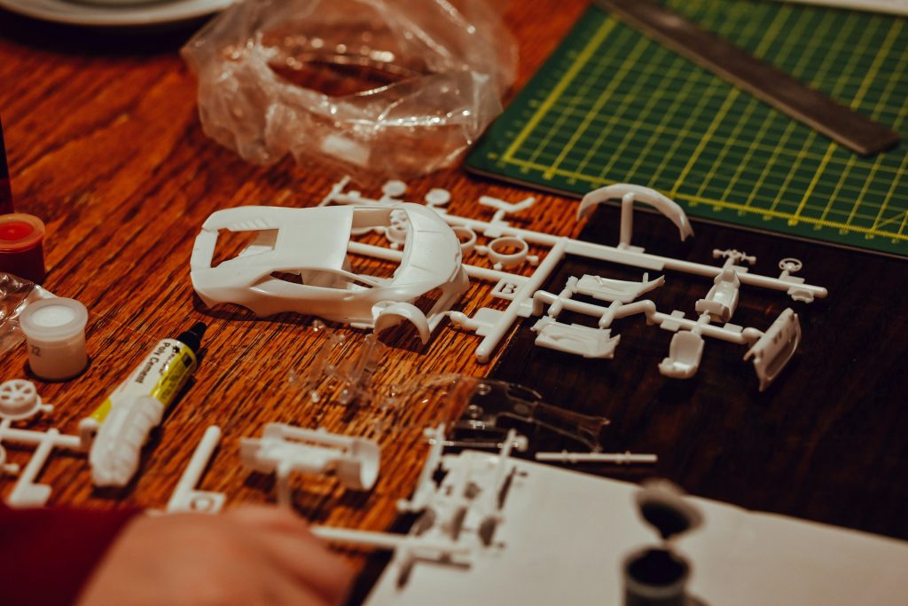 Hands assembling a detailed 3D-printed model car with many small parts
